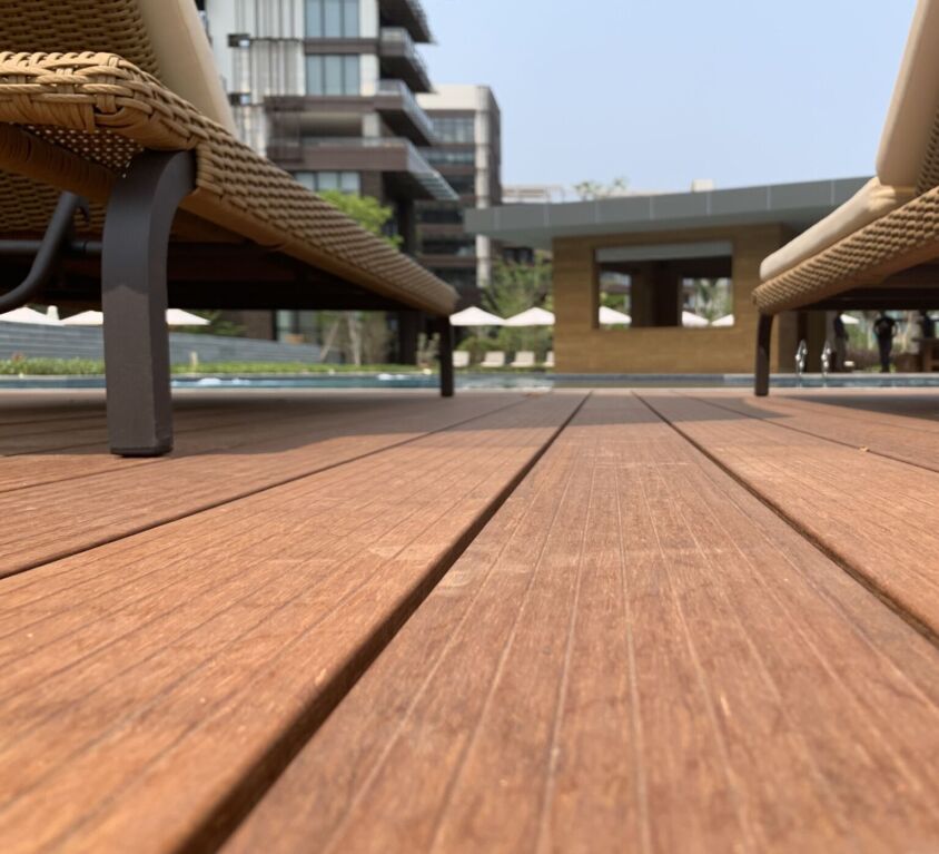 Chaises longues sur terrasse en bois, bâtiment moderne.