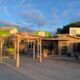 Devanture d'un bâtiment en bois avec pergola extérieure.