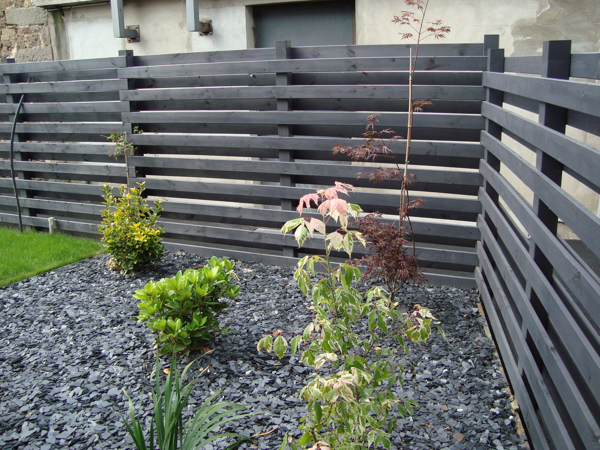 Jardin avec clôture en bois et plantes.