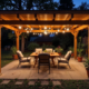 Pergola illuminée avec salon de jardin le soir.