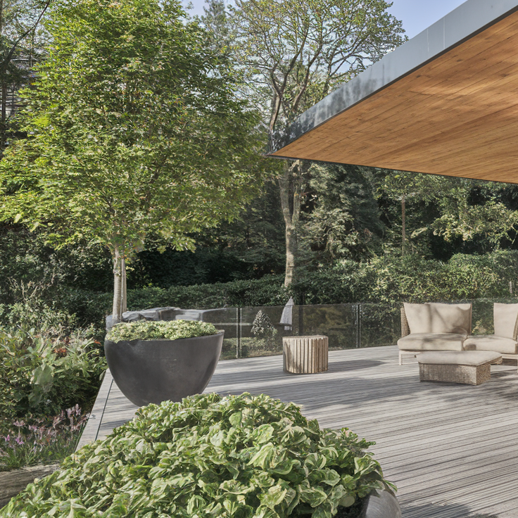 Terrasse en bois avec fauteuils et nature environnante.