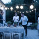 Dîner en terrasse avec amis sous guirlande lumineuse.