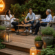 Groupe discutant sur une terrasse chaleureuse, boissons à main.