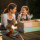 Mère et fille peignant une boîte en bois.