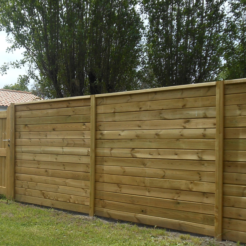 Clôture en bois devant arbres.