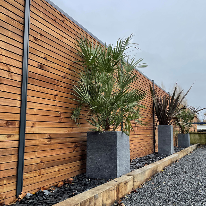 Jardin avec clôture en bois et plantes en pots.