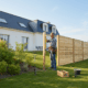 Homme installant une clôture en bois dans un jardin
