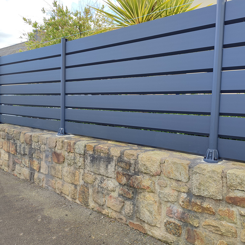 Clôture moderne en métal sur mur de pierre