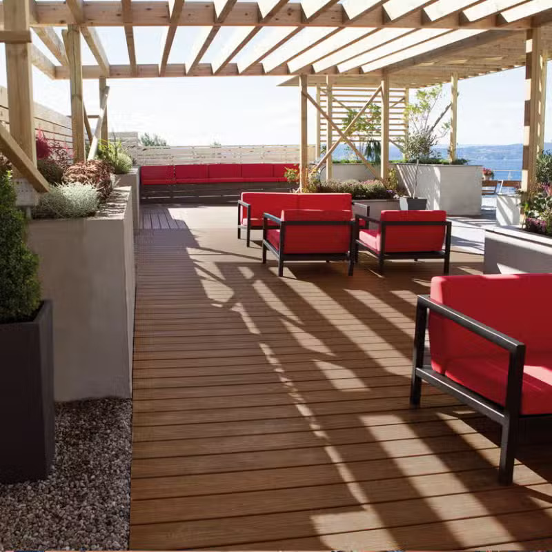 Terrasse avec fauteuils rouges et pergola en bois.