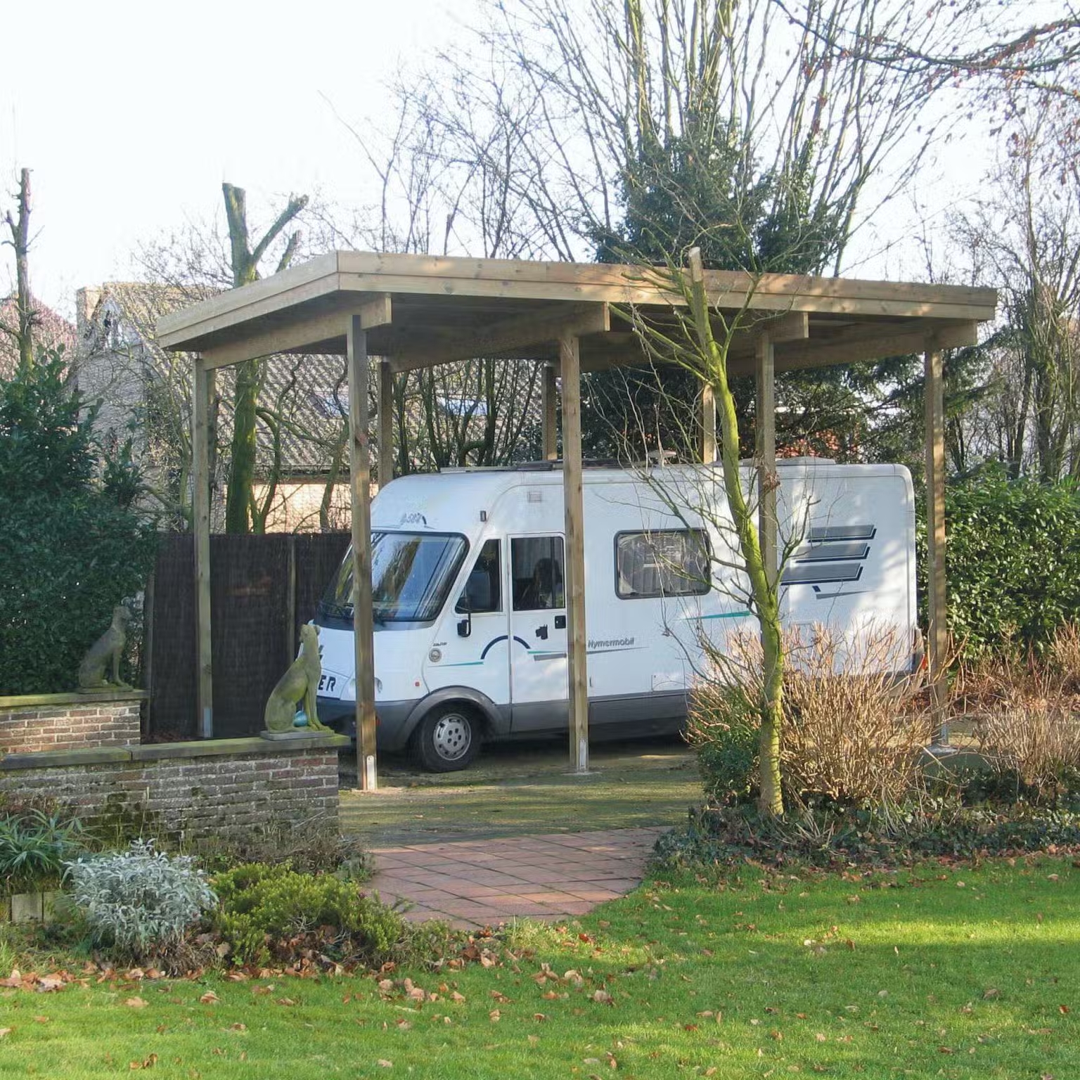 Camping-car stationné sous un abri en bois.