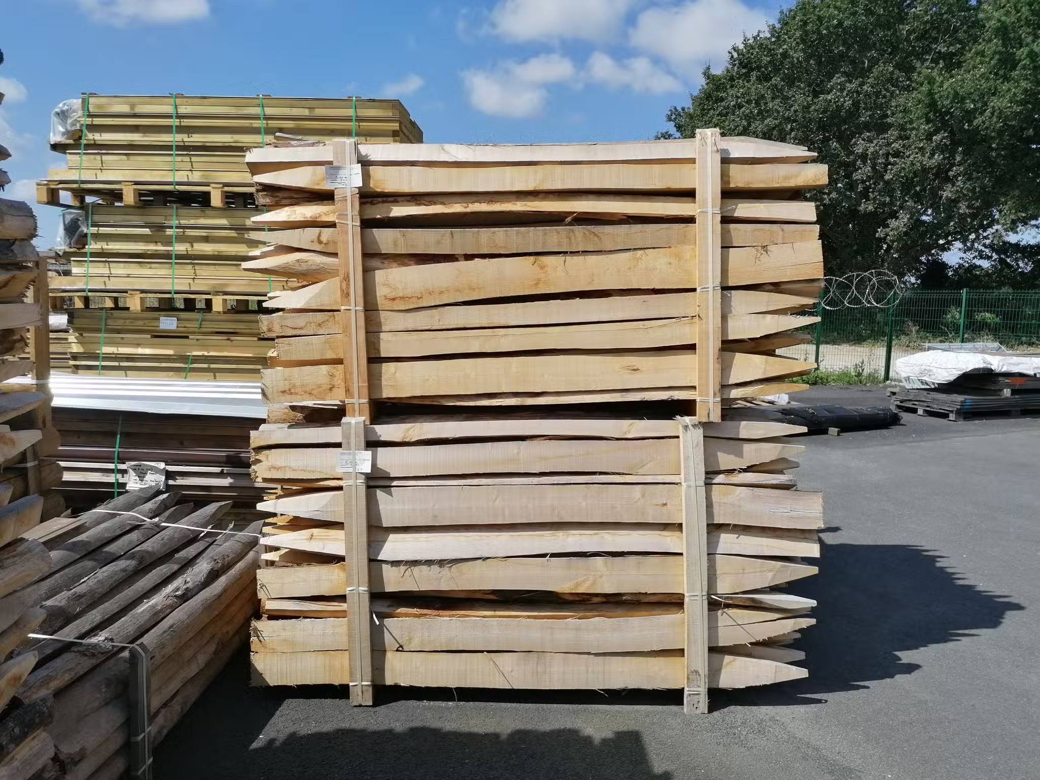 Pile de planches de bois stockées à l'extérieur.