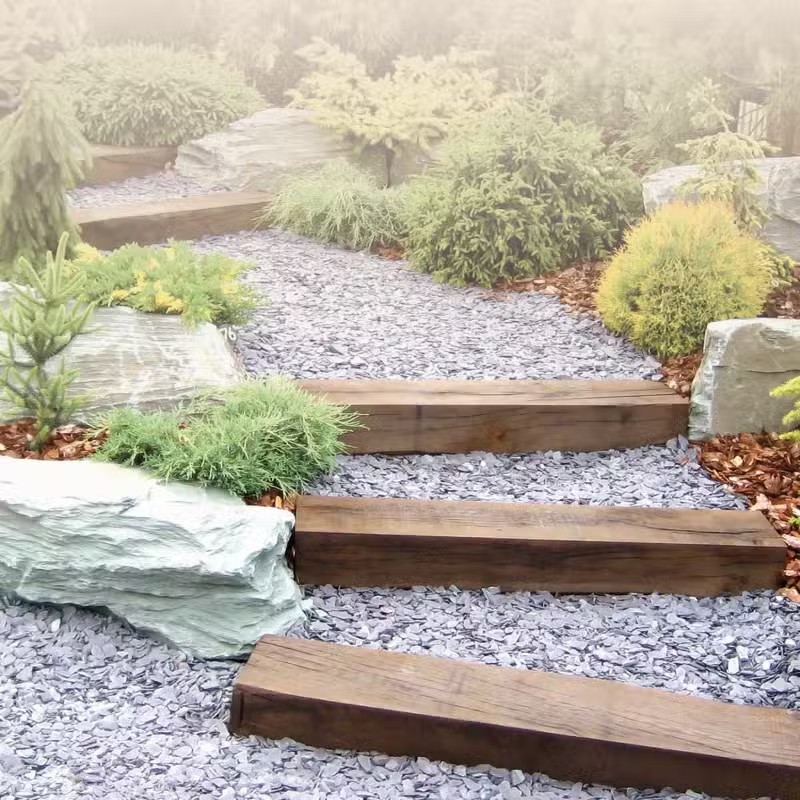 Chemin de jardin avec marches en bois et graviers.