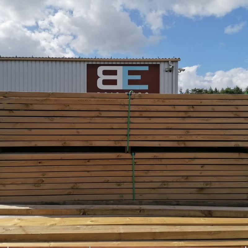 Pile de bois devant un entrepôt.