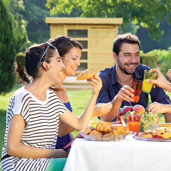 Personnes célébrant avec croissants et boissons en plein air.