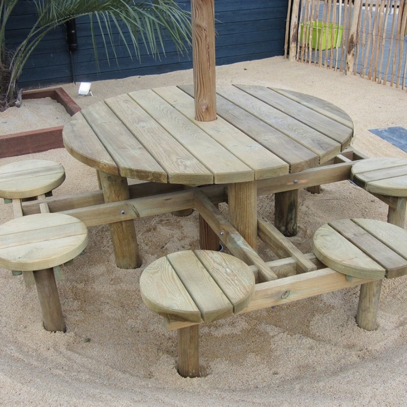 Table ronde en bois avec tabourets sur le sable.