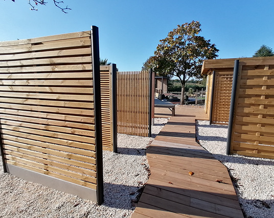 Chemin en bois entre clôtures de jardin.