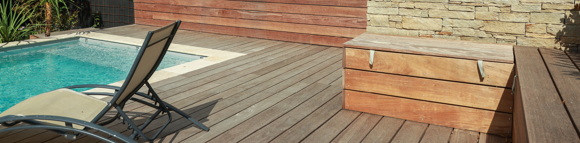 Terrasse en bois avec piscine et chaise longue.
