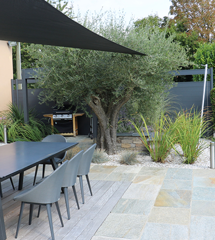 Jardin moderne avec terrasse et arbre au centre.