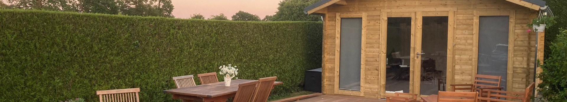 Jardin avec terrasse en bois devant un cabanon.