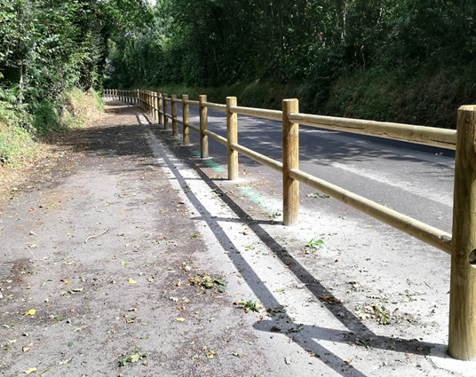Chemin forestier bordé de barrières en bois.