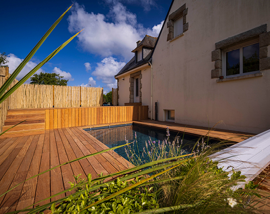 Terrasse en bois avec piscine près d'une maison.