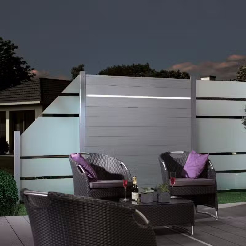 Terrasse nocturne avec mobilier moderne et clôture lumineuse.