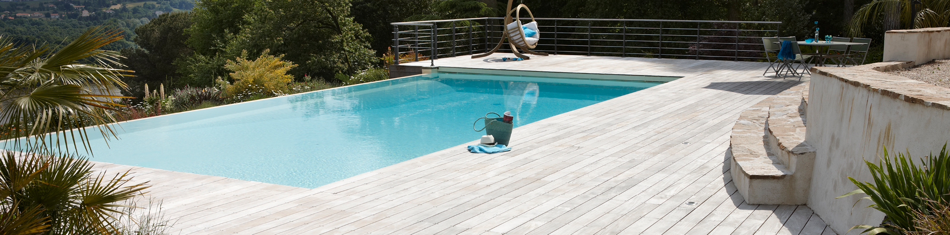 Piscine extérieure avec terrasse en bois et jardin.