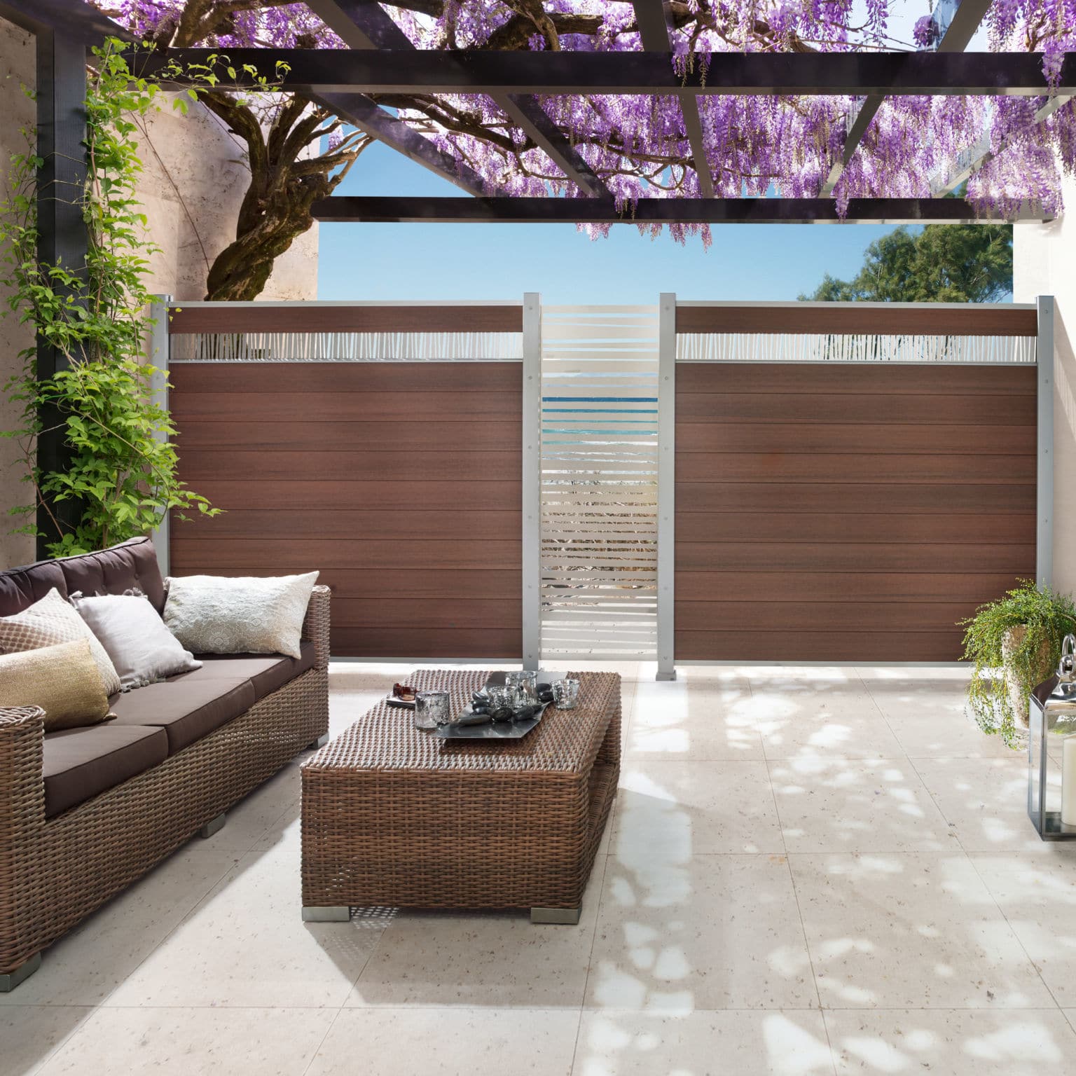 Terrasse avec canapé et glycines fleuries.