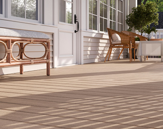 Terrasse en bois avec mobilier en rotin, maison blanche.